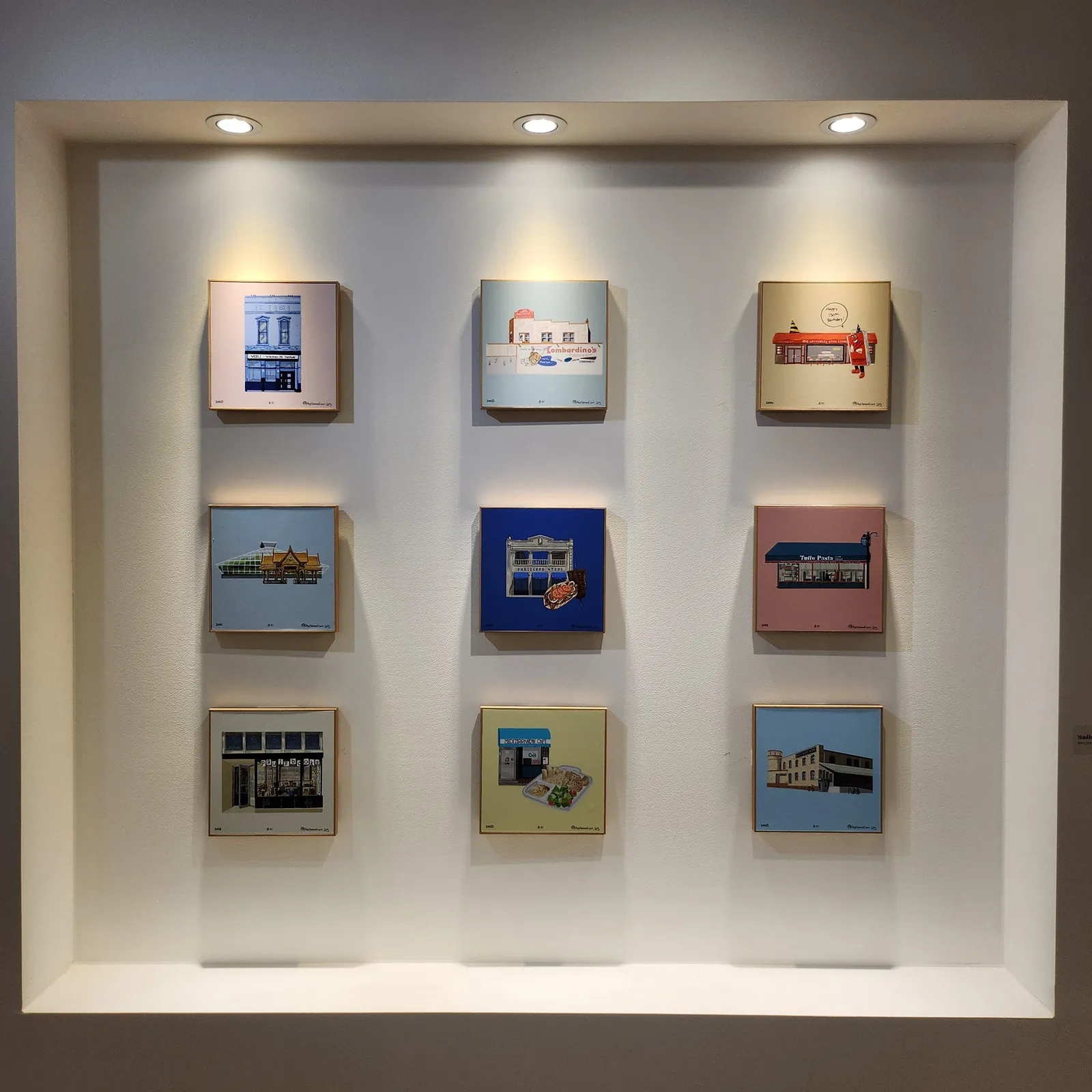 Nine small canvases in a lit display niche